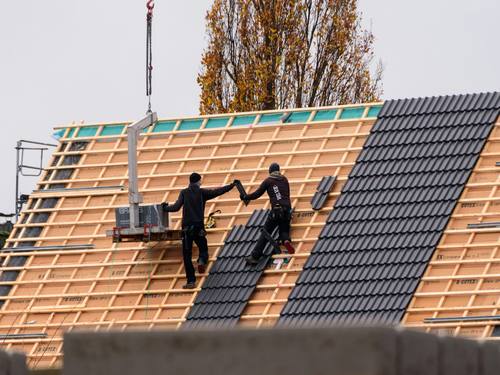 Artisan François, couvreur à Bourges (18000) dans le Cher, posant des tuiles sur une toiture en cours de réfection